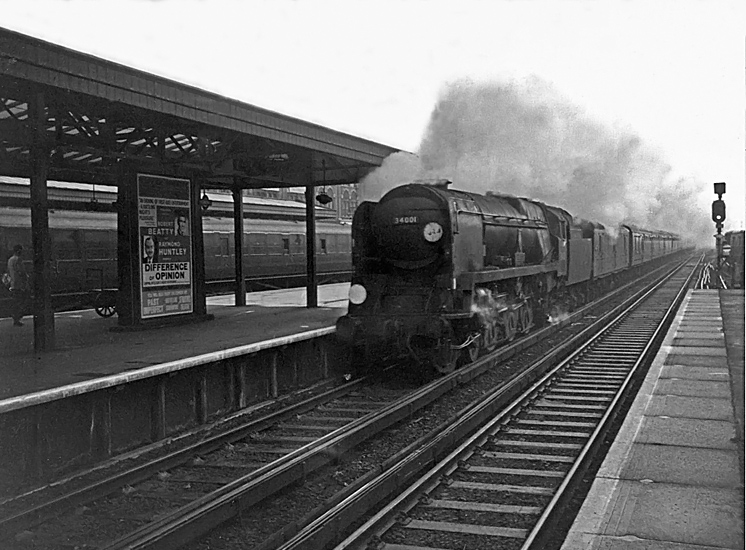 Photo of Bulleid West Country Class pacific number 34001, Exeter, racing though Woking with a London, Waterloo to Bournemouth line train in the mid 1960s