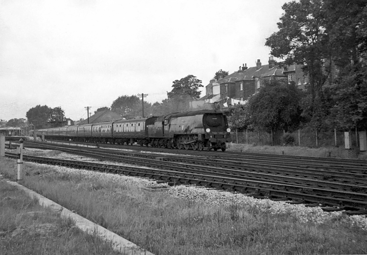 Photo of an original Bulleid Battle of Britain Class pacific number 34063, 229 Squadron, passing Millbrook, Southampton, with a Bournemouth to Reading and beyond interegional train, probably in 1963