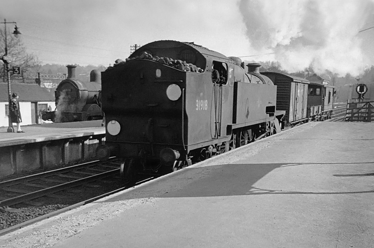 Photo of H class 0-4-4 tank loco number 31551 in the bay platform at Oxted as a W class 2-6-4 tank heads through in the London direction with a very short goods train, circa April 1962