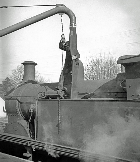 Photo of an H class 0-4-4 tank loco taking water in the bay platform at Oxted, 1962