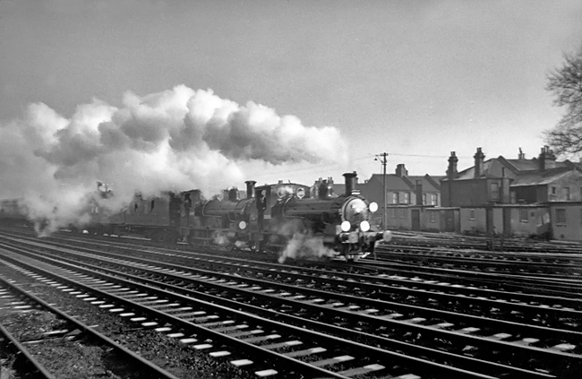 Photo of 0298 Class 2-4-0  well tank locos 30585 and 30587 leaving Wimbledon in December 1962