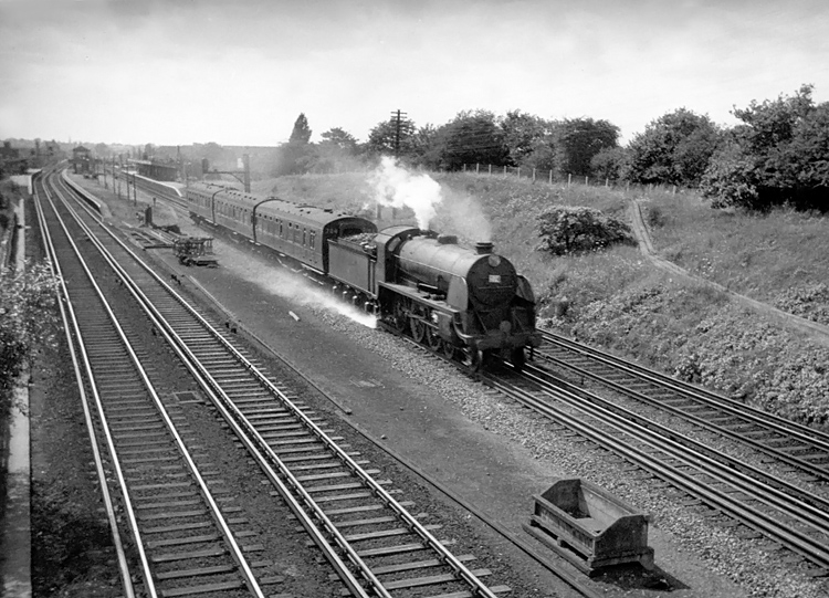 Photo of a Maunsell S15 class 4-6-0 hurrying a very lightweight up Salisbury local train through New Malden in 1962-1963