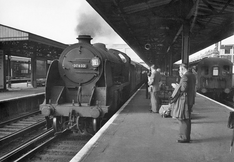 Photo of Maunsell S15 class 4-6-0 number 30833 arriving at Woking past a train of Bil units in the bay platform, when working an up Basingstoke local train for commuters in 1962-1963