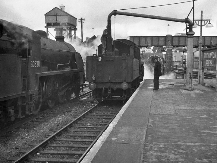 Photo of S15 class 4-6-0 number 30828 stopped at Southampton Central next to a BR Standard class 4 4-6-0 to take water whilst working an up ballast train in September 1962