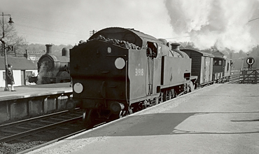 Photo of W Class 2-6-4 tank loco 31918 on a short goods train passing H Class 0-4-4-0 tank loco 31551 on a push pull train in the bay platform at Oxted. Spring 1962