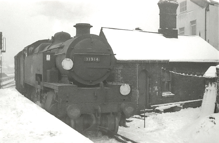 Photo of W Class 2-6-4 tank loco 31914 passing an Oxted line station near to Croydon in winter 1961/62